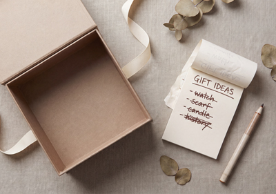 An empty gift box on a linen background along with a notepad