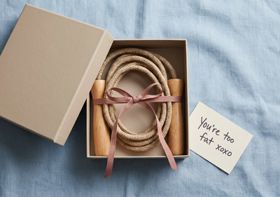 A jump rope inside a gift box on a blue linen background